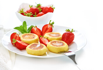 Cottage cheese pancakes, syrniki, ricotta fritters on ceramic plate with fresh strawberry.