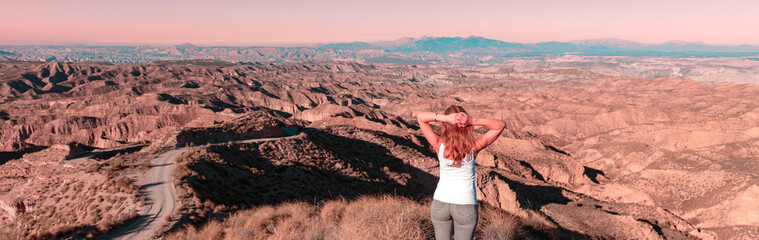 Fototapeta na wymiar Woman standing and looking at sunset Gorafe desert in Spain