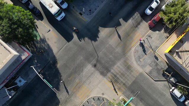 Overhead view of vehicles, including buses and a motorcycle going across the streets. People in crosswalks. businees traffic road