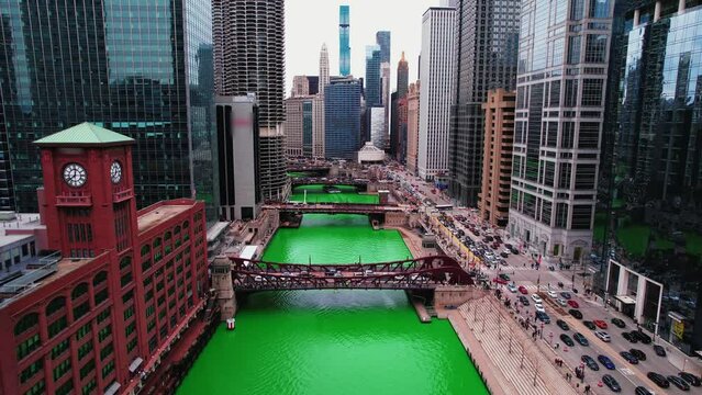 push in amazing chicago aerial between buildings downtown during the St. Patrick's Day Parade cinematic. Bascule bridges with famous chicago buildings in background. Logos blured. Aerial 4k USA