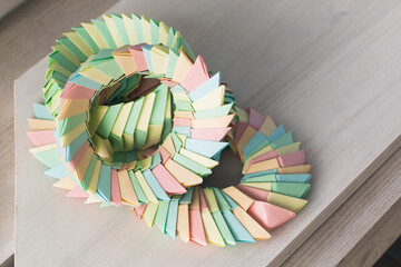 Origami rings made of colorful paper lay on a white wooden table