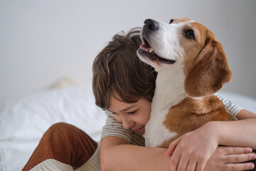 Happy boy embracing rescued beagle on bed, both smiling. adopt a loving pet and create lifelong...