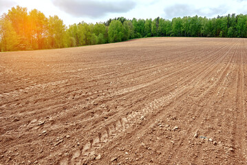 Plowed field in spring, agriculture rural landscape. Plough agriculture field. Countryside background, farm field and sunny sky. - obrazy, fototapety, plakaty