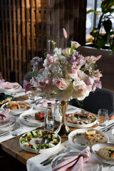 served table in the restaurant is decorated with a luxurious bouquet. Garden roses, eustoma, populus eucalyptus. pastel colours