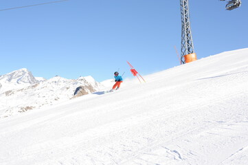 Skier in blue jacket, black helmet and orange pants on the piste slope in winter with snow...