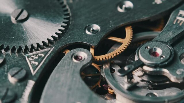 Clock mechanism rotates close-up. The working mechanism of round stopwatch spinning in macro. Detailed view of old retro clockwork gears, cogwheels and pendulum movement inside the ancient metal watch