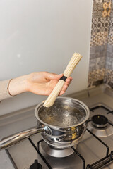 A girl is cooking udon in a pot on the stove