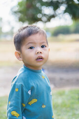 Portrait of a little boy looking into the camera. Children's emotions. Boy with black eyes playing outdoors. Happy Asian child toddler boy smiling close up looking at camera. Education Concept.