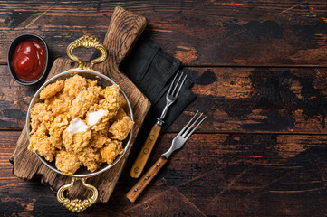 Homemade Crispy Popcorn Chicken bites in a skillet. Wooden background. Top view. Copy space