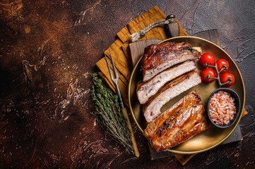 Chopped BBQ pork ribs  on a plate with herbs. Dark background. Top view. Copy space