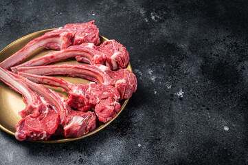 Lamb chop rib steak, raw mutton meat cutlet in golden plate. Black background. Top view. Copy space
