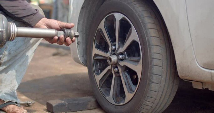 The mechanic is bringing the tool used to unscrew the wheel nut before using the air impact wrench because the size of the air impact wrench is larger than normal,it requires an adapter to change size