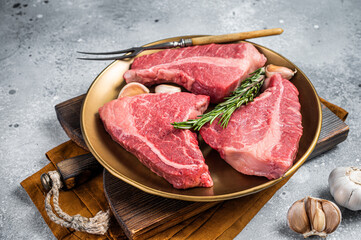 Raw Topside sirloin beef cut on steel plate with spices. Gray background. Top view