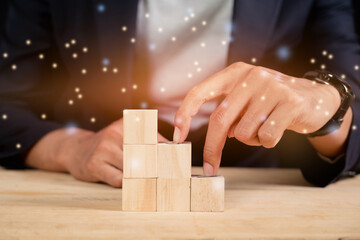 A business man with his fingers climbing a ladder from wooden cubes on the table