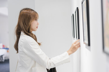 Woman visiting art gallery her looking pictures on wall watching photo frame painting at artwork museum people lifestyle concept.