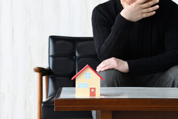 家づくり失敗イメージ―住宅の模型と悩む男性