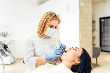 Female dentist with female patient in dental chair providing oral cavity treatment.