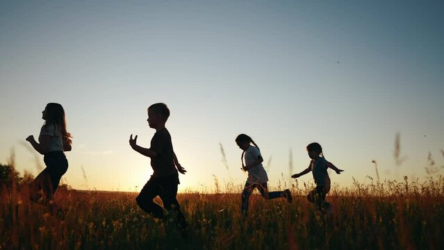 Children running in park at sunset. happy family kindergarten kids dream concept. Kids running in grass silhouette lifestyle. children playing outdoors silhouette. Kids playing in the park at sunrise
