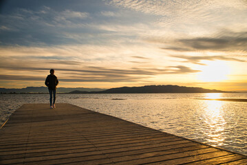 Girl walking along the dock watching the sunset in the ebro delta