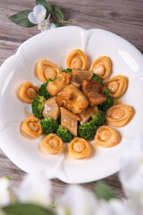 expensive premium braised head abalone with sea cucumber and flower mushroom broccoli in thick golden sauce on wood table asian chinese halal deluxe banquet seafood menu 