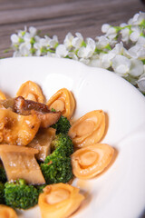 expensive premium braised head abalone with sea cucumber and flower mushroom broccoli in thick golden sauce on wood table asian chinese halal deluxe banquet seafood menu 