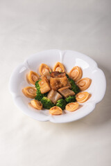 expensive premium braised head abalone with sea cucumber and flower mushroom broccoli in thick golden sauce on wood table asian chinese halal deluxe banquet seafood menu 