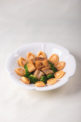 expensive premium braised head abalone with sea cucumber and flower mushroom broccoli in thick golden sauce on wood table asian chinese halal deluxe banquet seafood menu 