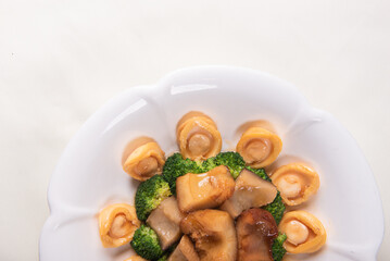 expensive premium braised head abalone with sea cucumber and flower mushroom broccoli in thick golden sauce on wood table asian chinese halal deluxe banquet seafood menu 