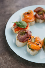 Exotic wine appetizers served on plate. Canapes with salmon fish and sliced meat prepared for eating