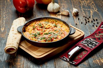 Menemen with eggs, tomato, green peppers, and spices served with bread in pan. Turkish breakfast