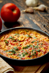 Menemen with eggs, tomato, green peppers, and spices served with bread in pan. Turkish breakfast