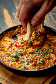 Menemen with eggs, tomato, green peppers, and spices served with bread in pan. Turkish breakfast