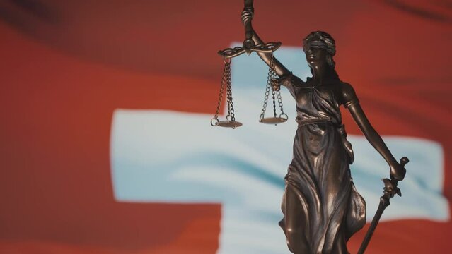 The Statue of Justice - lady justice, Justitia the Roman goddess of Justice. Woman of law. Swiss flag and justice system