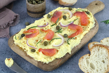 Butter board with red fish, capers, red onions, spices, herbs and bread on blue background. Party, finger food. 