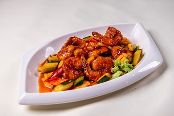 wok fried red sweet and sour spicy sauce with big prawn  and cucumber on wood table chinese banquet seafood halal menu