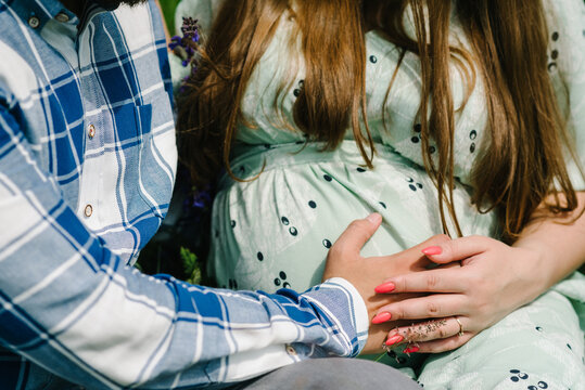 Waiting baby. Husband hand embraces a round belly pregnant wife. Parenthood. Closeup. nine months. Cropped image pregnant woman and loving handsome man hugging tummy. Loving Couple.
