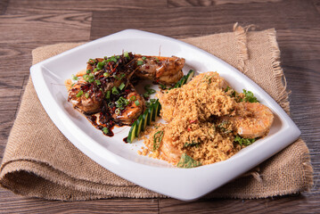 two in one varieties wok fried big prawn with nonya sweet and sour dark sauce and cereal butter prawn with curry leaf on wood table chinese halal banquet seafood menu