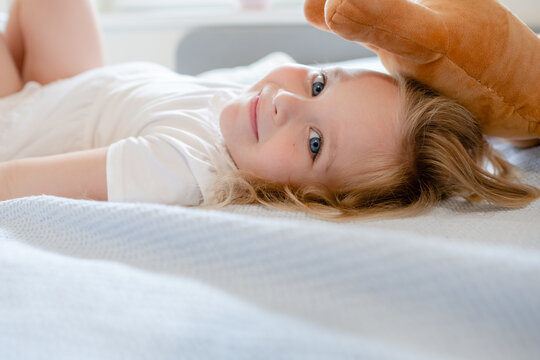 Little girl lying in bed and looking at the camera