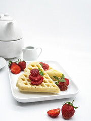Selective focus of Waffles garnished with strawberries on a white plate with white background