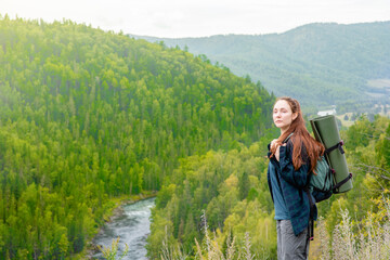 Naklejka na ściany i meble Young woman with backpack enjoys the view of nature at hike. Empty space for text