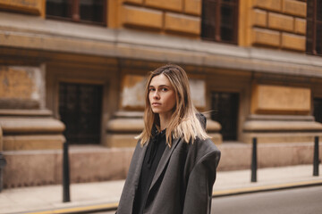 Photo of cute charming young woman wear grey jacket, calm walking outside city street. Girl look at camera.