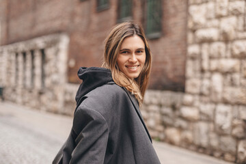 Young beautiful smiling hipster woman in trendy outfit. Sexy carefree woman posing on the street. Cheerful and happy girl wear grey suit and black hoodie turn around. Lifestyle, female beauty concept.