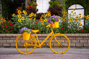 Yellow bicycle with flowers in a garden