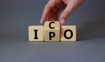 ICO vs IPO symbol. Businessman hand turns wooden cubes and changes the word IPO to ICO. Beautiful grey background. ICO vs IPO and business concept. Copy space