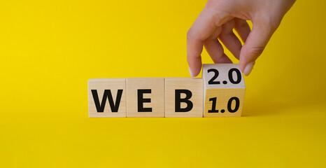 WEB 2 or 1 symbol. Businessman hand Turnes cube and changes word WEB 1.0 to WEB 2.0. Beautiful yellow background. Business and WEB concept. Copy space