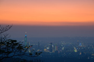 Fantasy orange sky. The vibrant and bustling night scene of Taipei City. Night view of the city surrounded by mountains is hazy and dreamy. Dajianshan, Taiwan