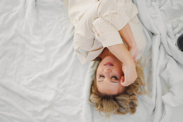 attractive blonde in white and delicate pajamas in bed. top view