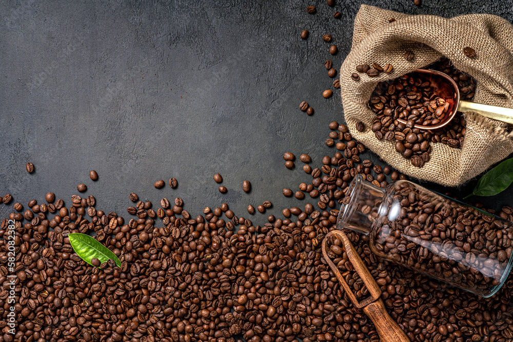 Wall mural scoop of coffee beans in a bag on dark background. top view of coffee in a cup. copy space for text
