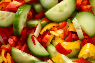 Fresh vegetables cucumbers red yellow peppers sliced in salad