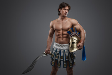 Shot of isolated on grey background muscular warrior with sword and plumed helmet.